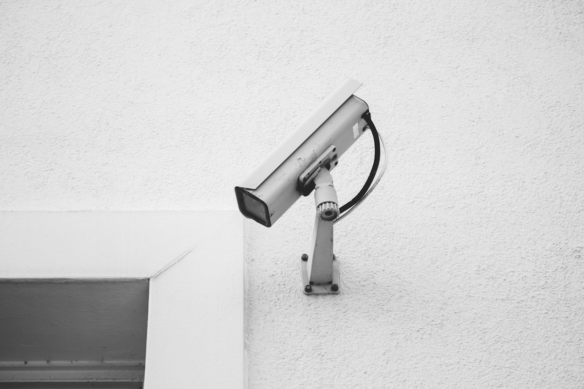 Illustrative white security camera mounted on a wall